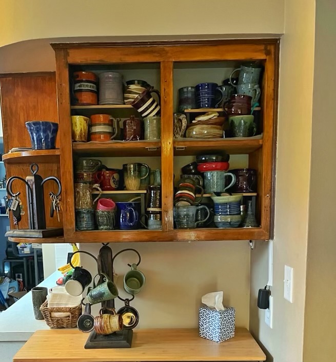 kitchen cabinet filled with a pile of mugs