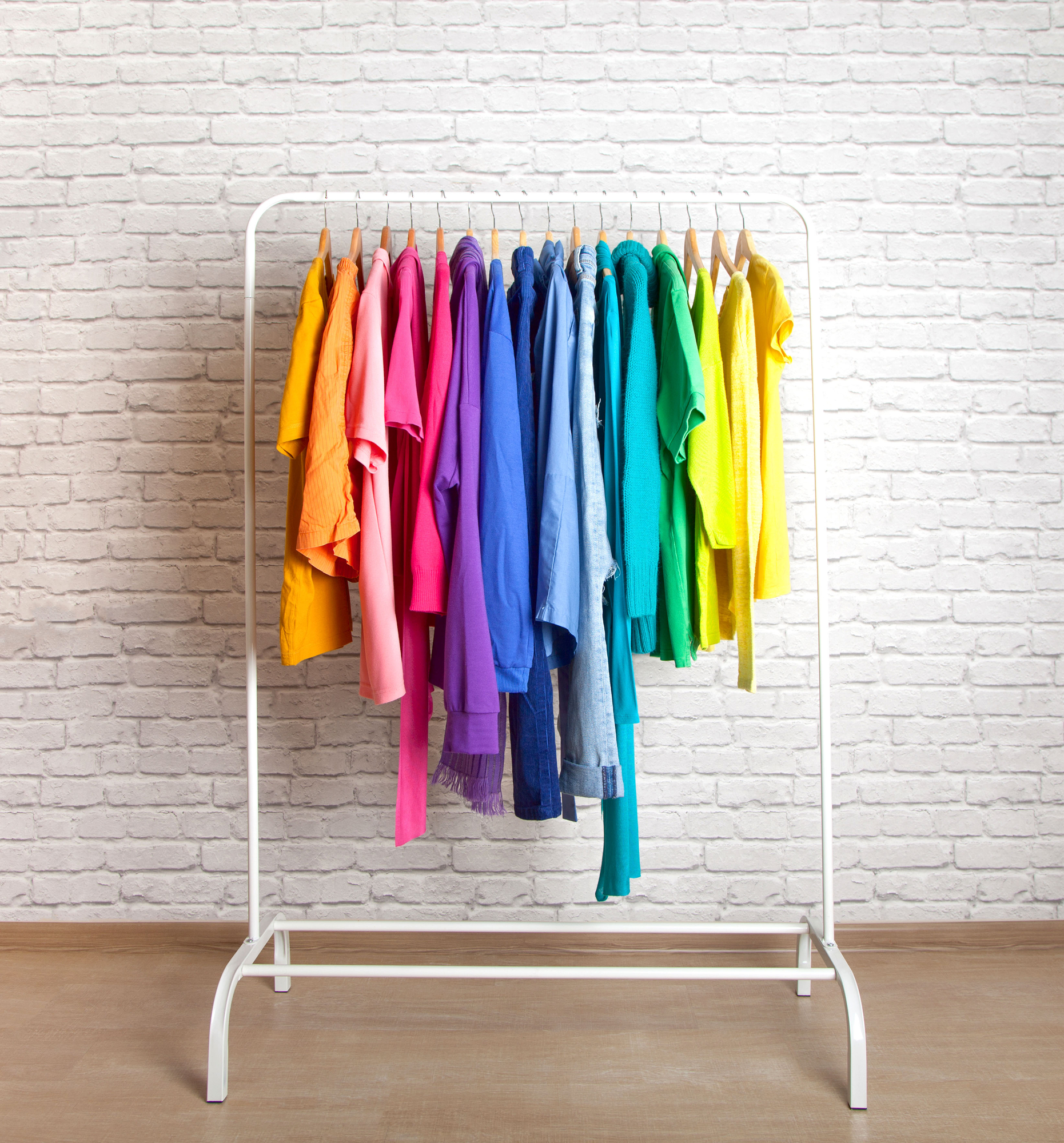 clothes on rack organized by the colors of the rainbow