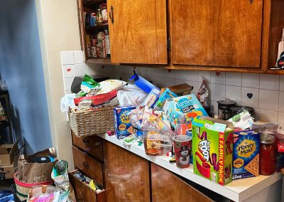dirty kitchen with counters overflowing with trash and food