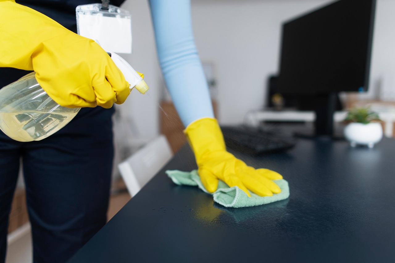 woman with yellow cleaning gloves wiping a surface
